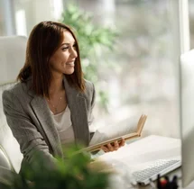 Collaboratrice prenant des notes dans un carnet à son bureau
