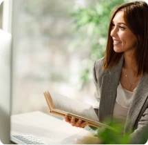 Collaboratrice prenant des notes dans un carnet à son bureau
